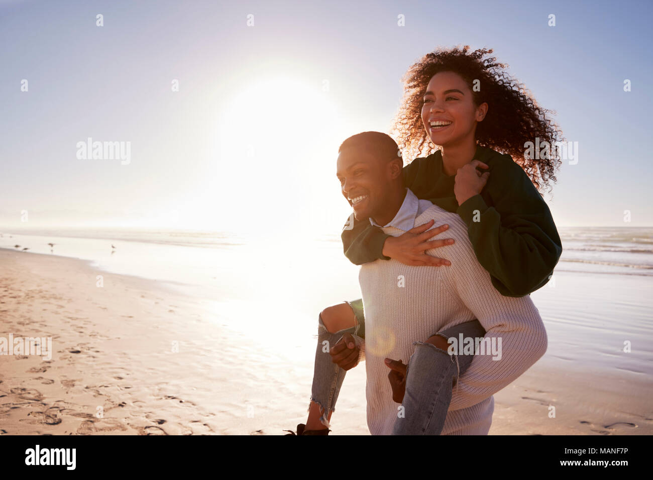 Mann, Frau, Huckepack auf Winter Urlaub am Strand Stockfoto
