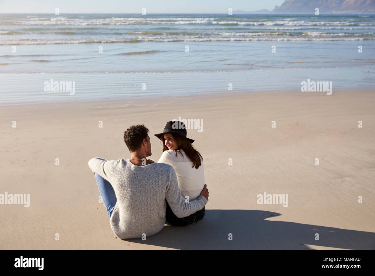 Romantisches Paar im Winter Strand sitzen zusammen Stockfoto