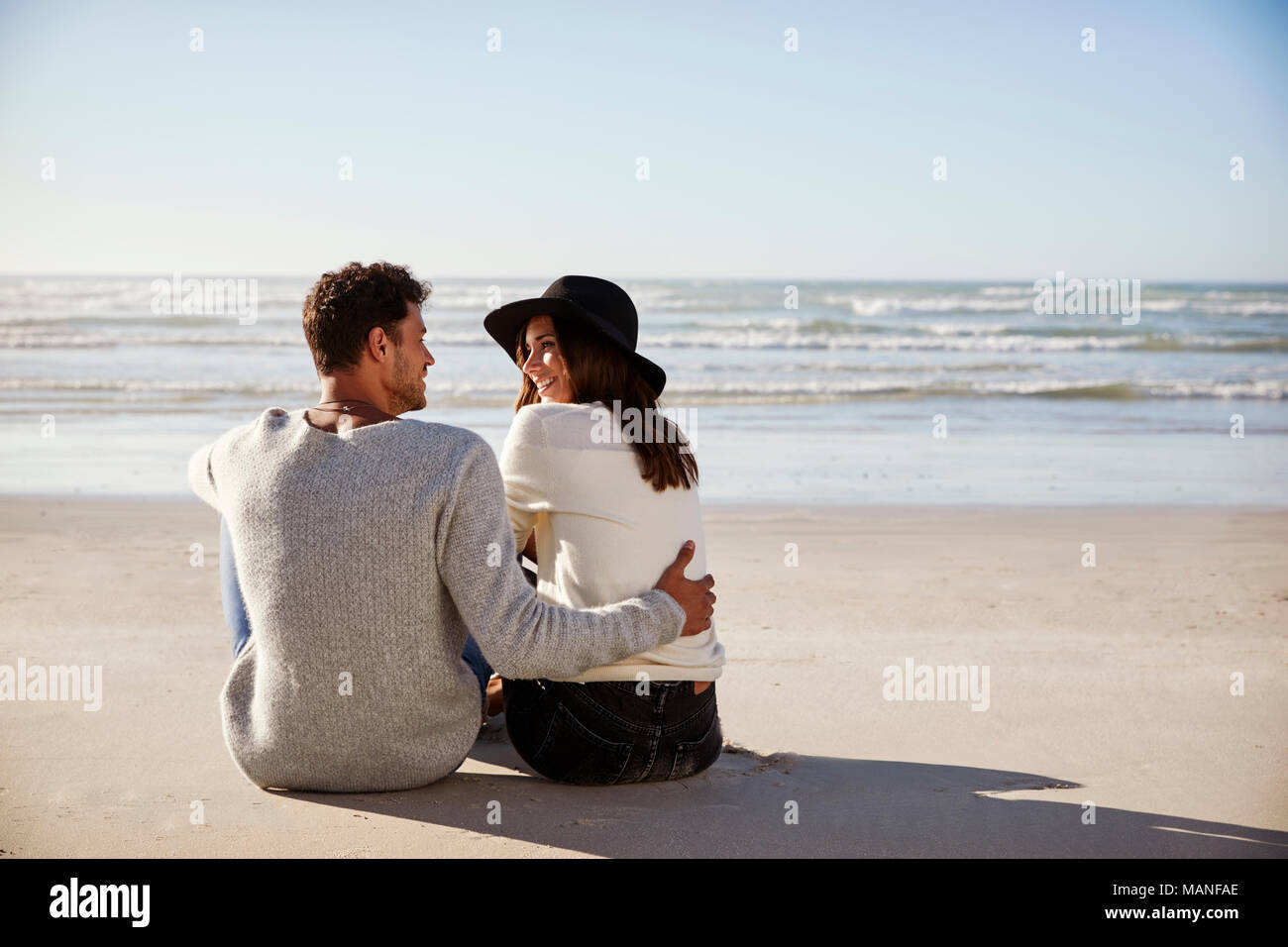 Romantisches Paar im Winter Strand sitzen zusammen Stockfoto