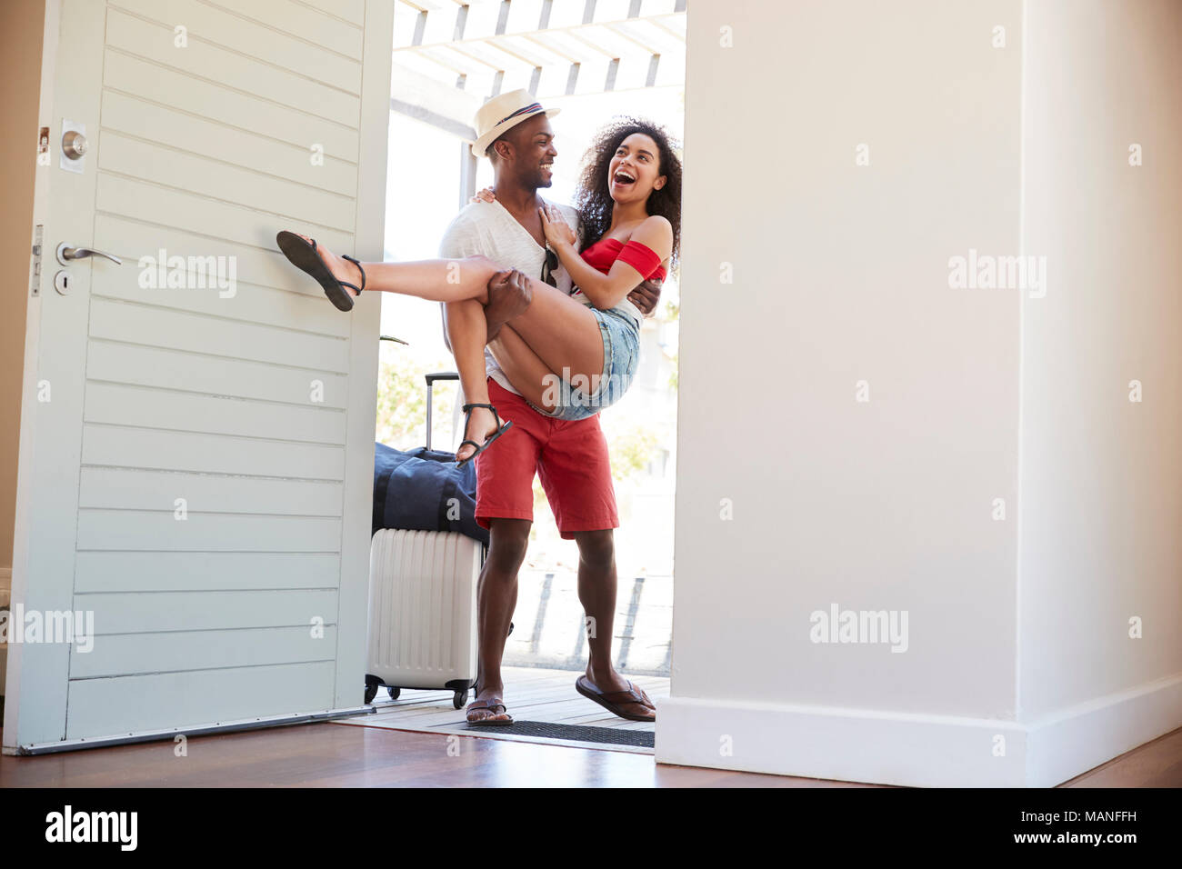 Der Mensch trägt Frau über dem Schwellenwert von Honeymoon Mietwagen Stockfoto