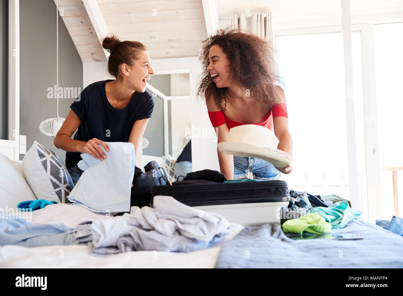 Zwei Freundinnen im Schlafzimmer packen Koffer für den Urlaub Stockfoto