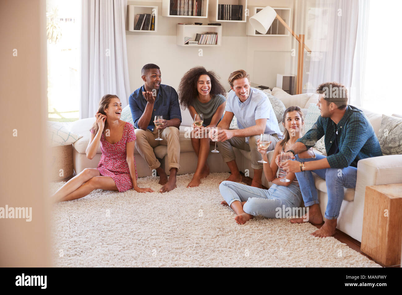 Gruppe von Freunden entspannt zu Hause und trinken Wein zusammen Stockfoto