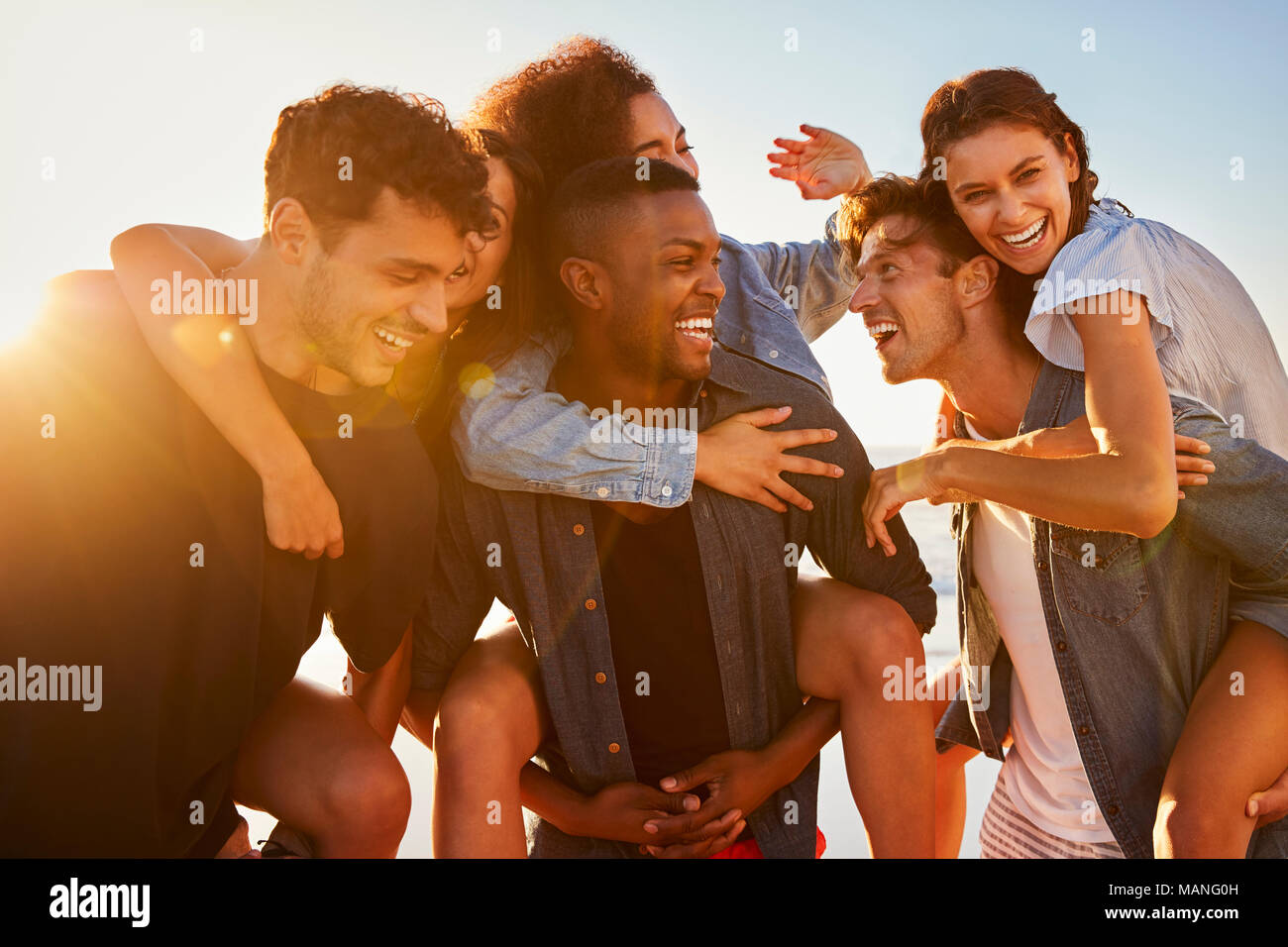 Eine Gruppe von Freunden auf Urlaub in Huckepack Rennen am Strand Stockfoto
