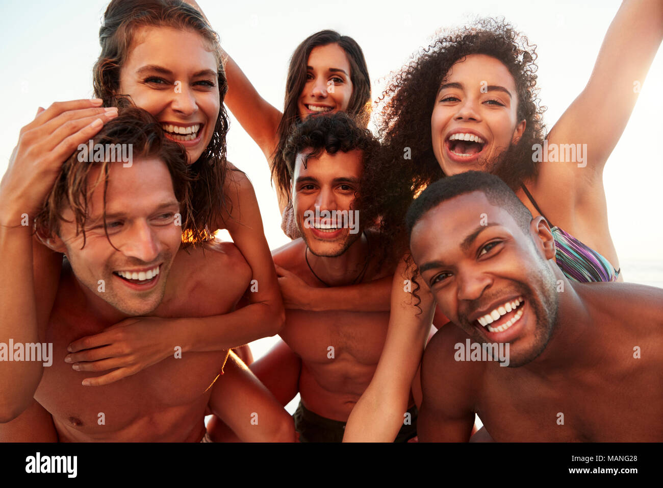 Eine Gruppe von Freunden auf Urlaub in Huckepack Rennen am Strand Stockfoto