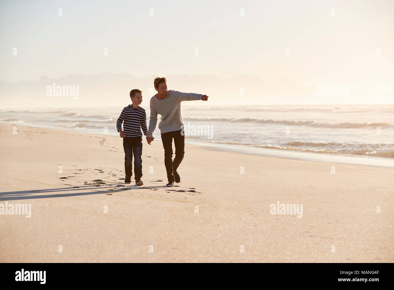 Vater und Sohn gehen entlang Winter Strand Hand in Hand Stockfoto