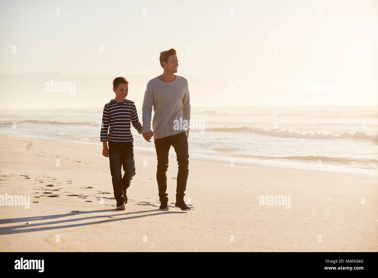 Vater und Sohn gehen entlang Winter Strand Hand in Hand Stockfoto