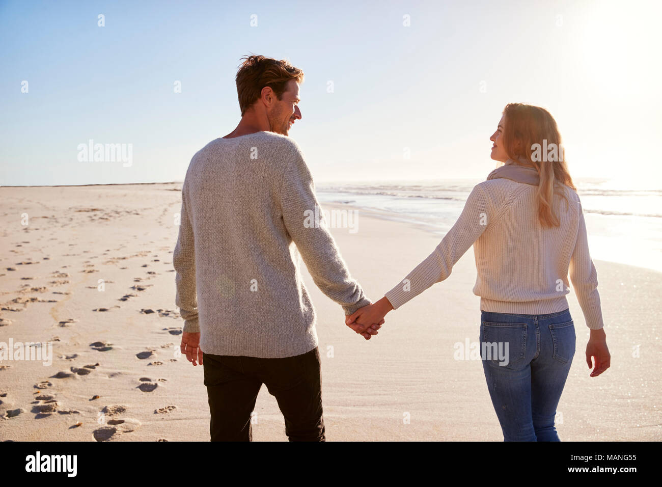 Ansicht der Rückseite des liebenden Paar entlang Winter Beach zusammen Wandern Stockfoto