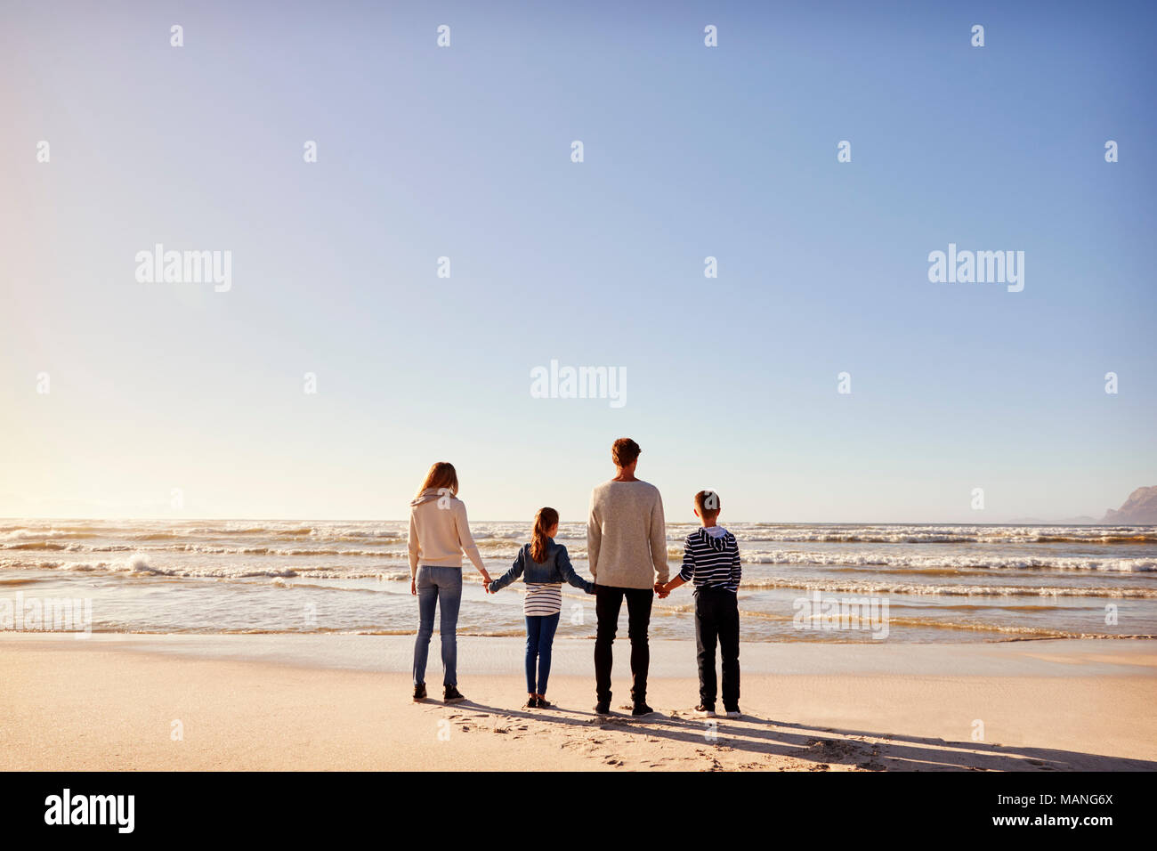 Ansicht der Rückseite des Familie im Winter Strand Hand in Hand mit Blick auf das Meer Stockfoto