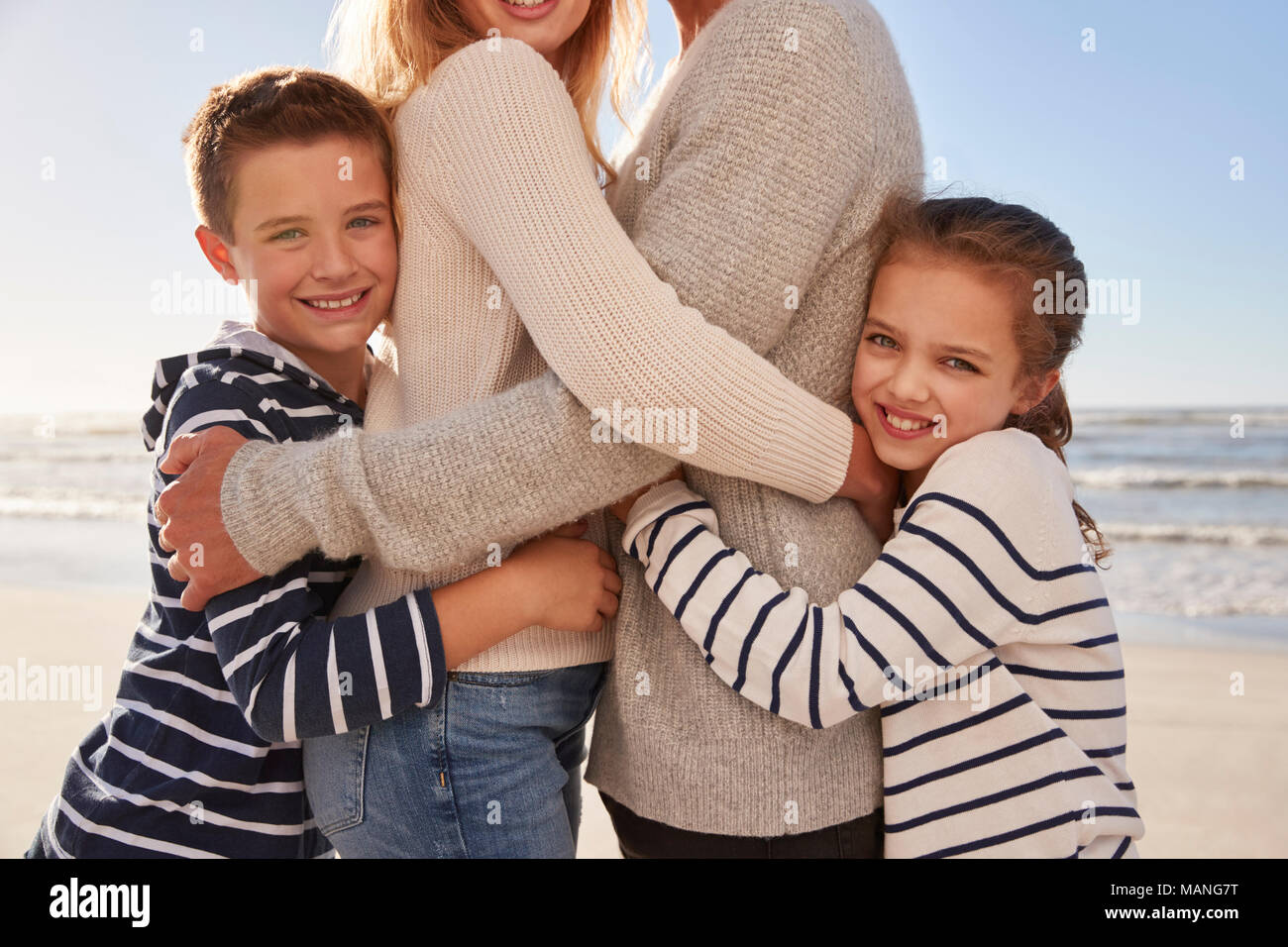 Nahaufnahme der Kinder umarmen Eltern auf Winter Strand Stockfoto