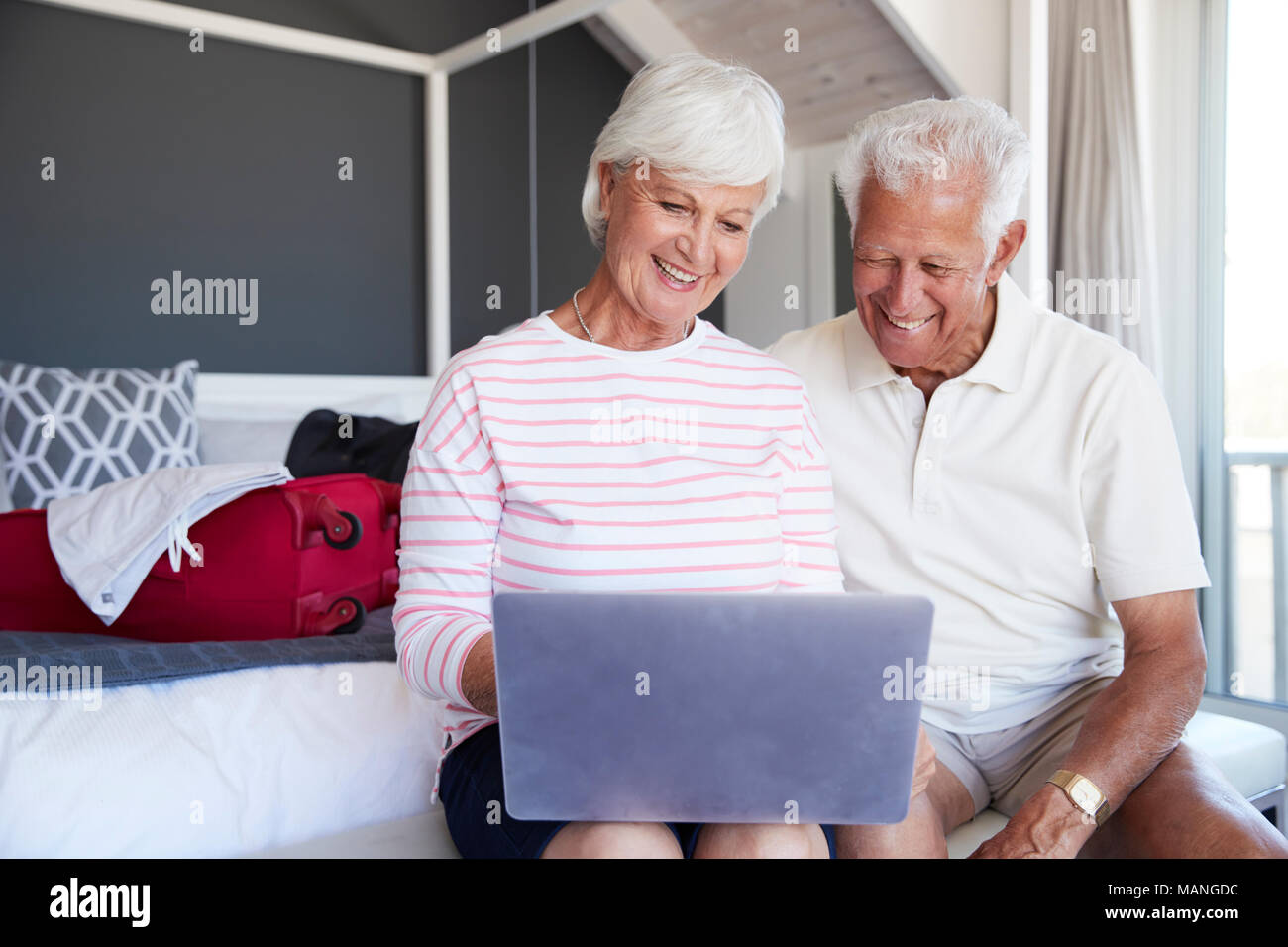 Älteres Ehepaar am Laptop schauen, wie Sie in der Wohnung überprüfen Stockfoto