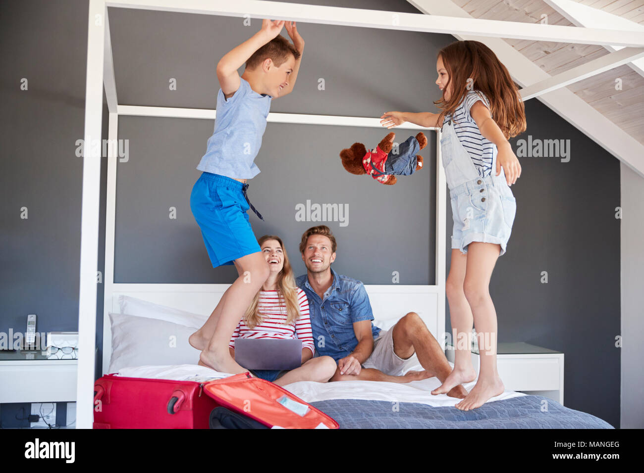Begeistert Kinder springen auf dem Bett als Eltern Pack für Ferienhäuser Stockfoto