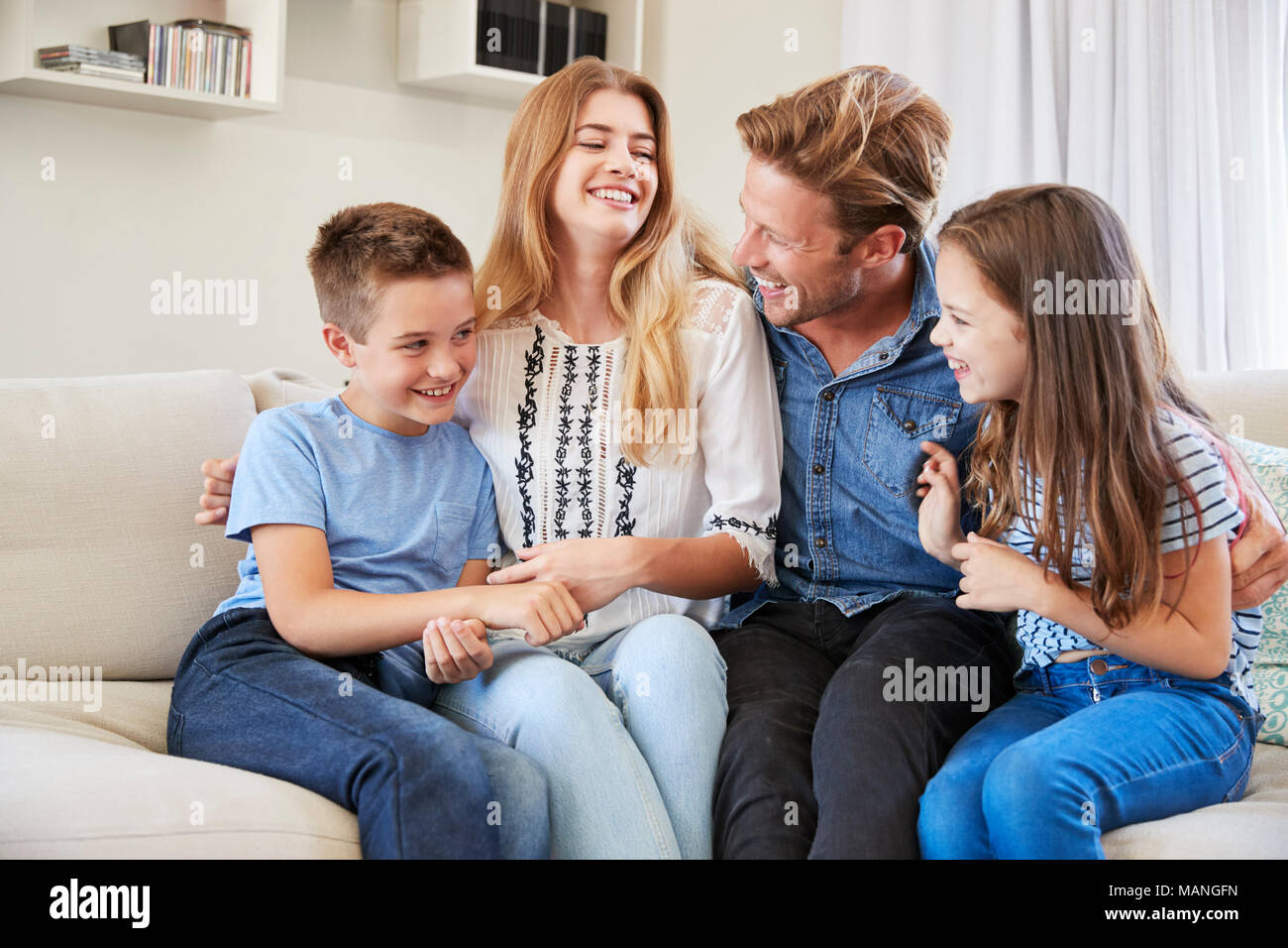 Lächelnd Familie entspannt auf einem Sofa zu Hause zusammen Stockfoto