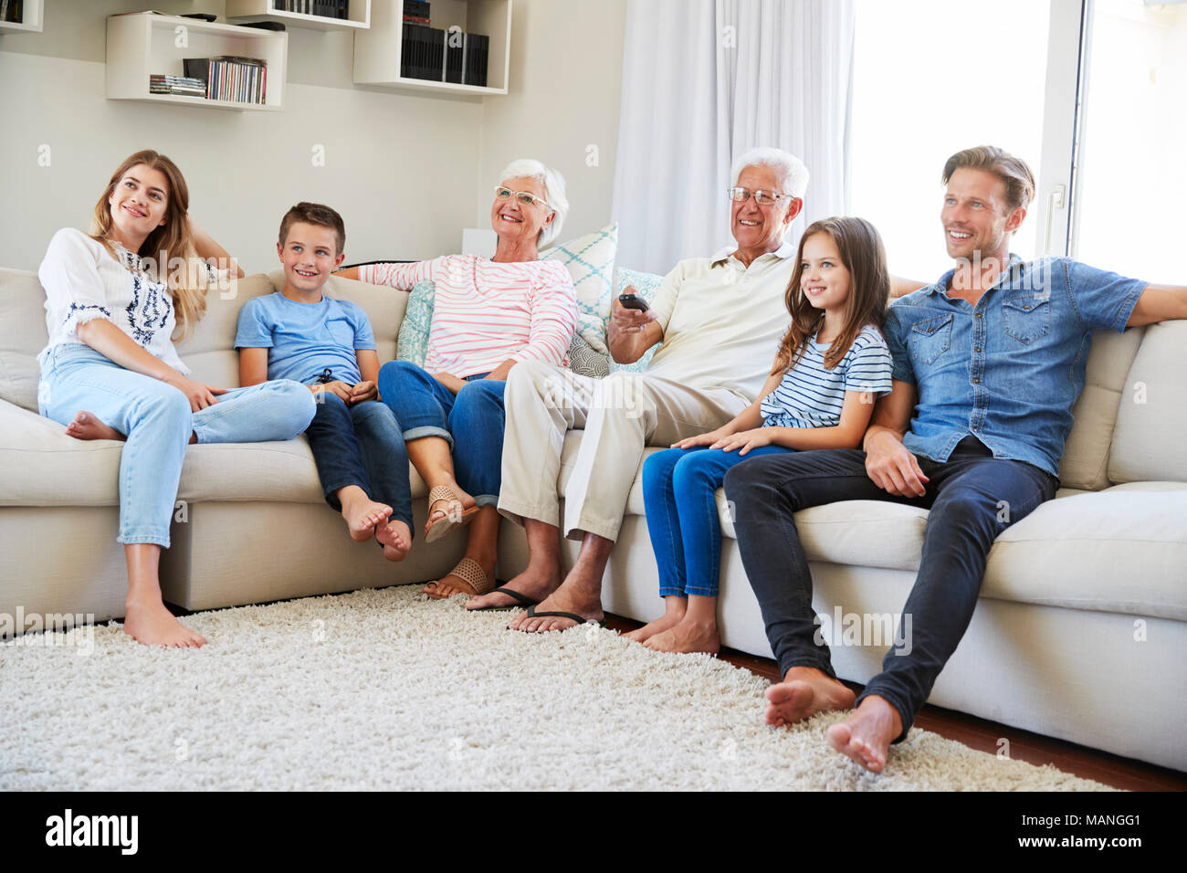 Multi-Generation Familie sitzt auf dem Sofa zu Hause Fernsehen Stockfoto