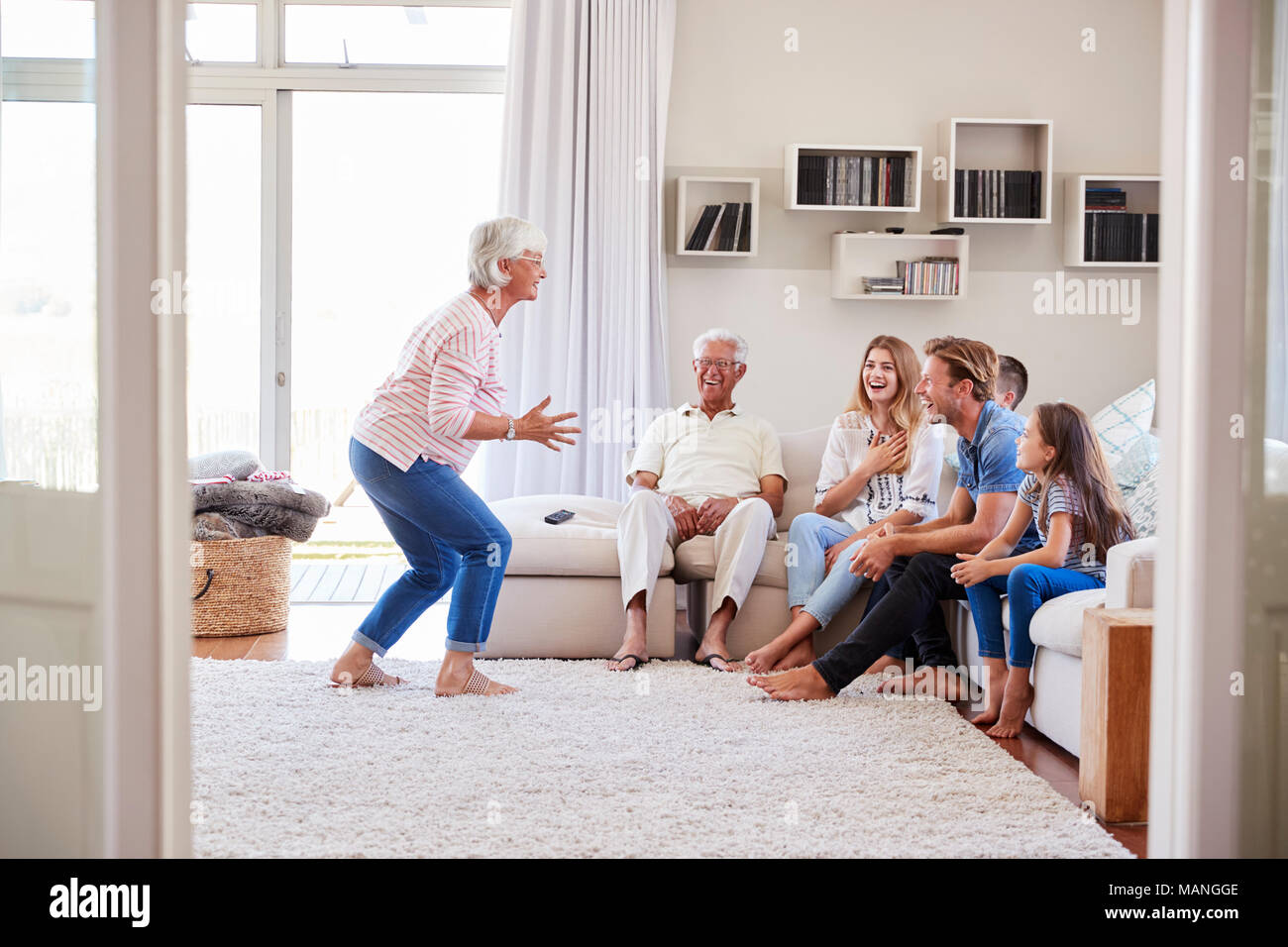 Multi-Generation Familie sitzt auf dem Sofa zu Hause spielt Scharaden Stockfoto