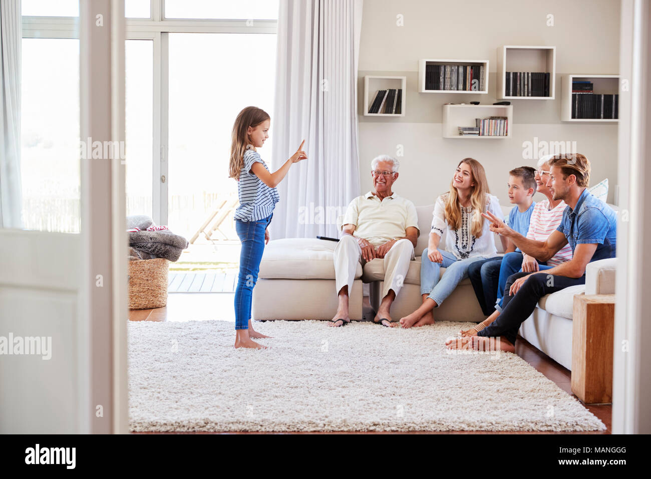 Multi-Generation Familie sitzt auf dem Sofa zu Hause spielt Scharaden Stockfoto