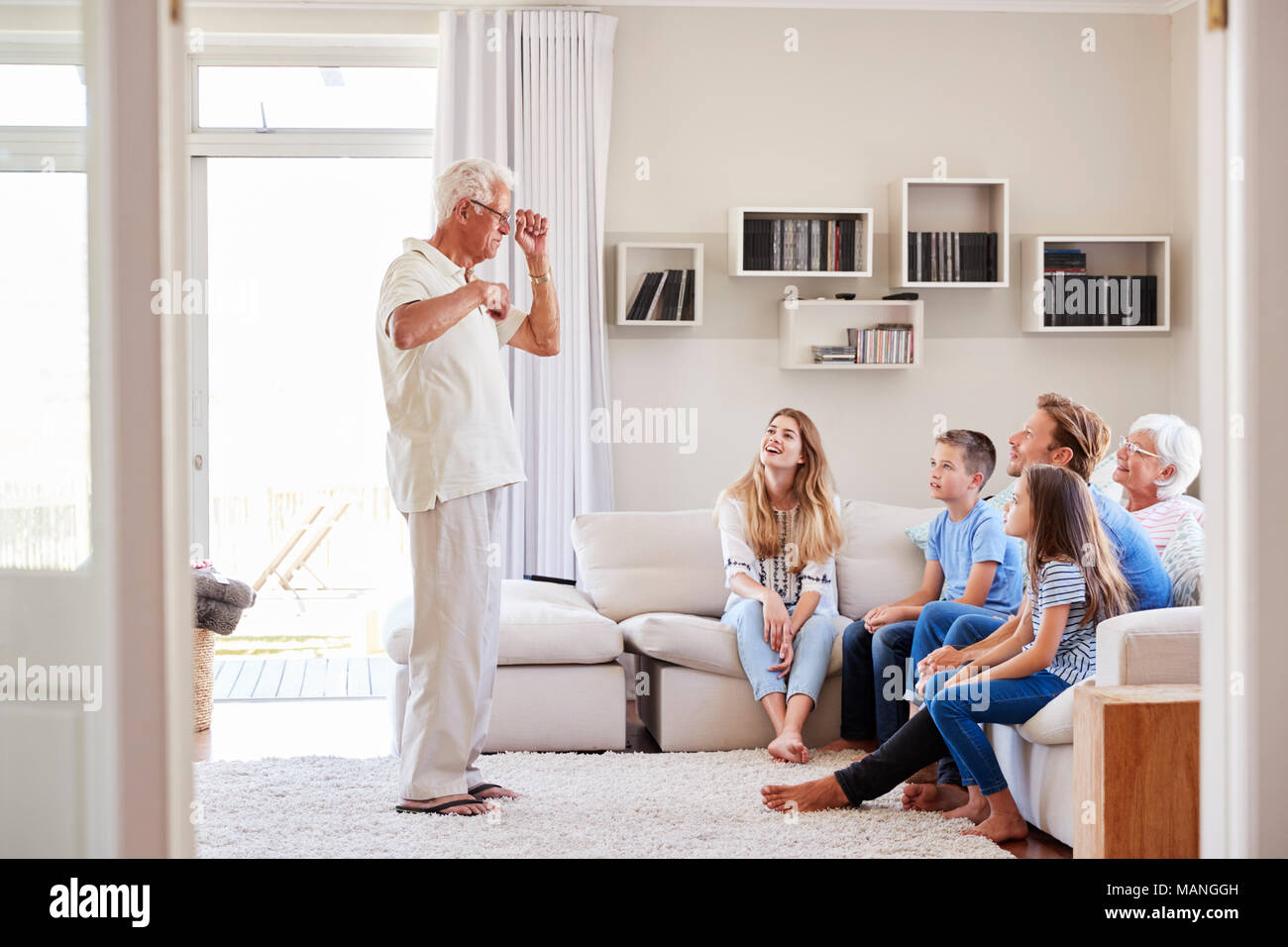 Multi-Generation Familie sitzt auf dem Sofa zu Hause spielt Scharaden Stockfoto