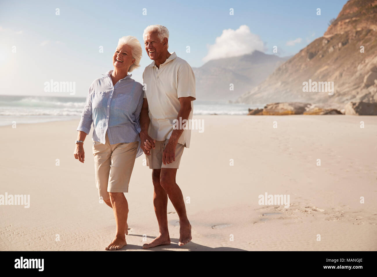 Älteres Rentnerehepaar Strand entlang gehen Hand in Hand Stockfoto