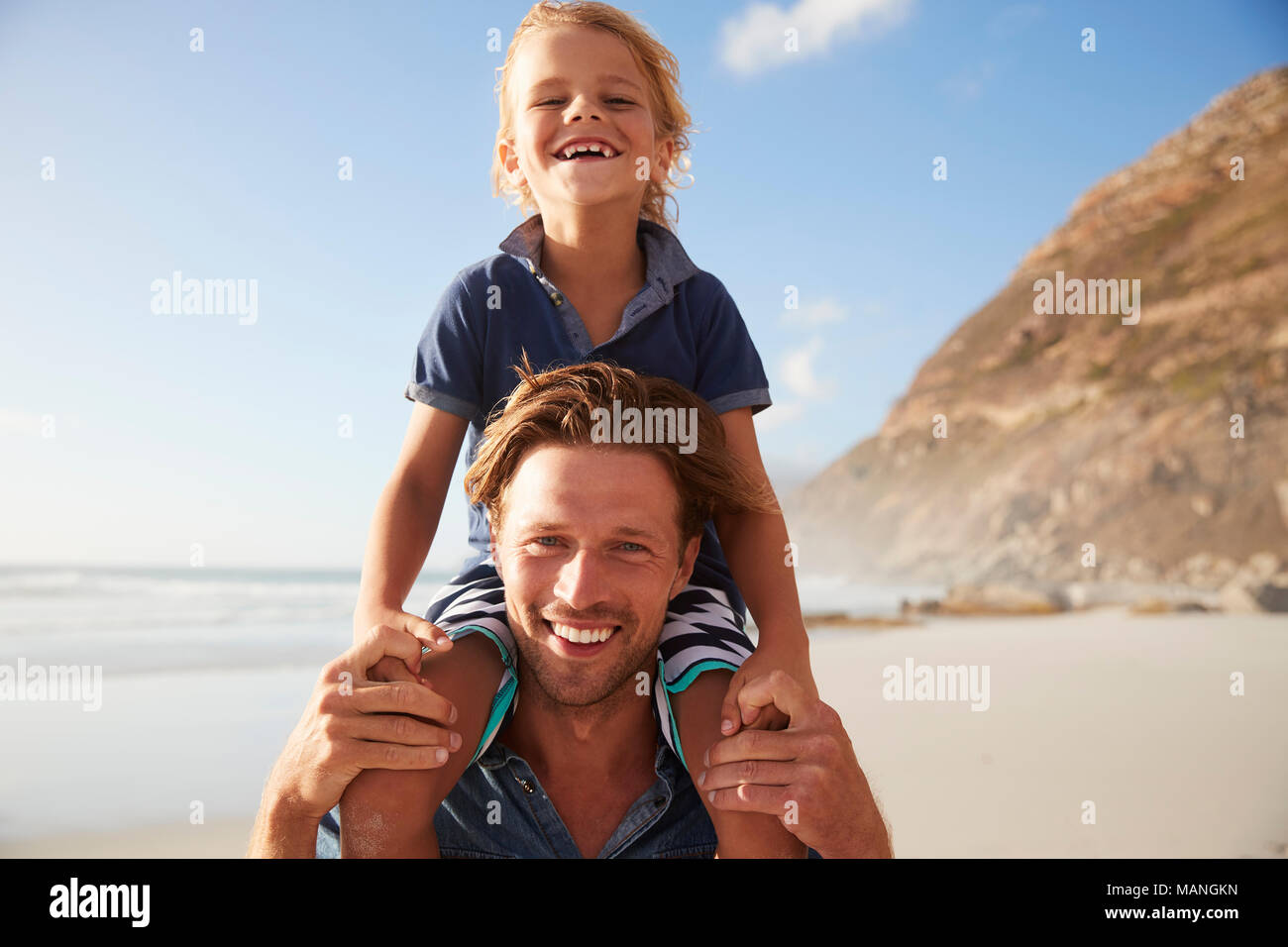 Portrait von Vater mit Sohn auf den Schultern am Strand Ferienhäuser Stockfoto