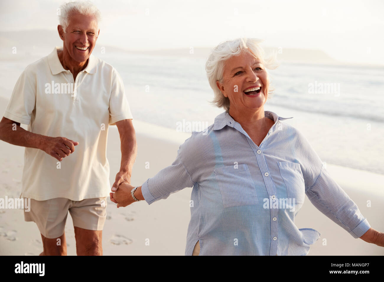 Älteres Rentnerehepaar Entlang Strand Hand in Hand zusammen Stockfoto