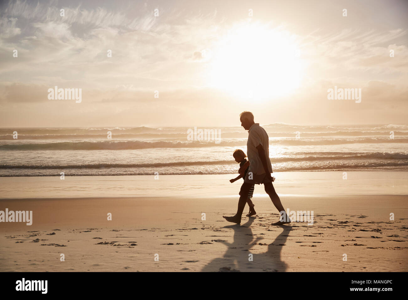 Silhouette der Großvater mit Enkel am Strand entlang zu laufen Stockfoto