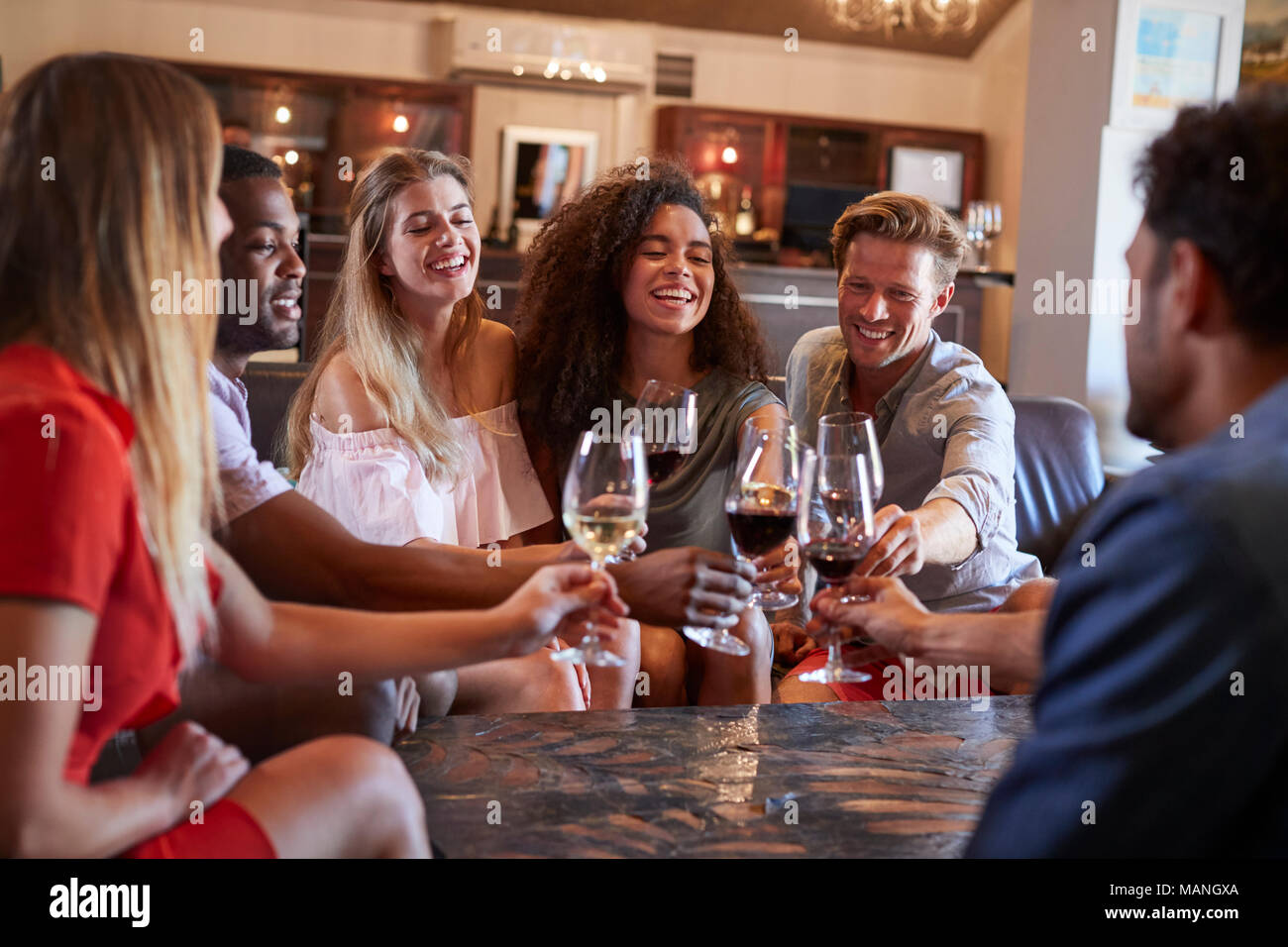 Sechs junge Erwachsene einen Toast mit Wein an der Bar Stockfoto