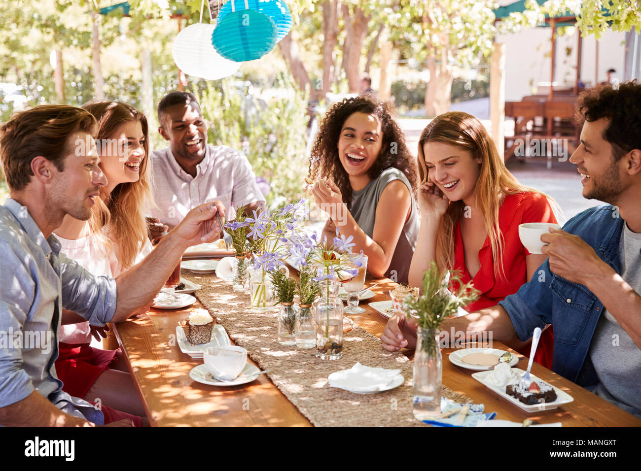 Sechs junge Freunde Speisen an einem Tisch im Freien Stockfoto