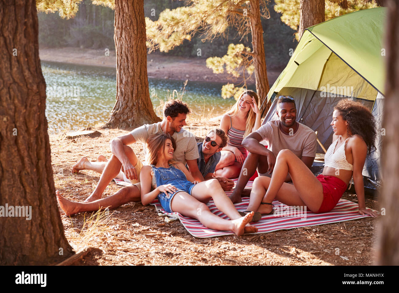 Freunde auf einer kampierenden Reise entspannen auf einer Decke an einem See Stockfoto