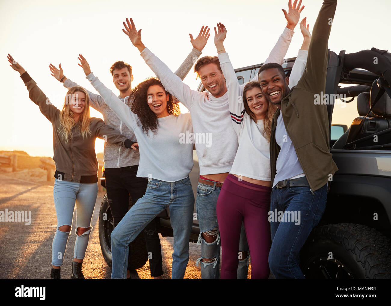 Junge Erwachsene Freunde mit den Händen in der Luft stehend mit dem Jeep, Nahaufnahme Stockfoto