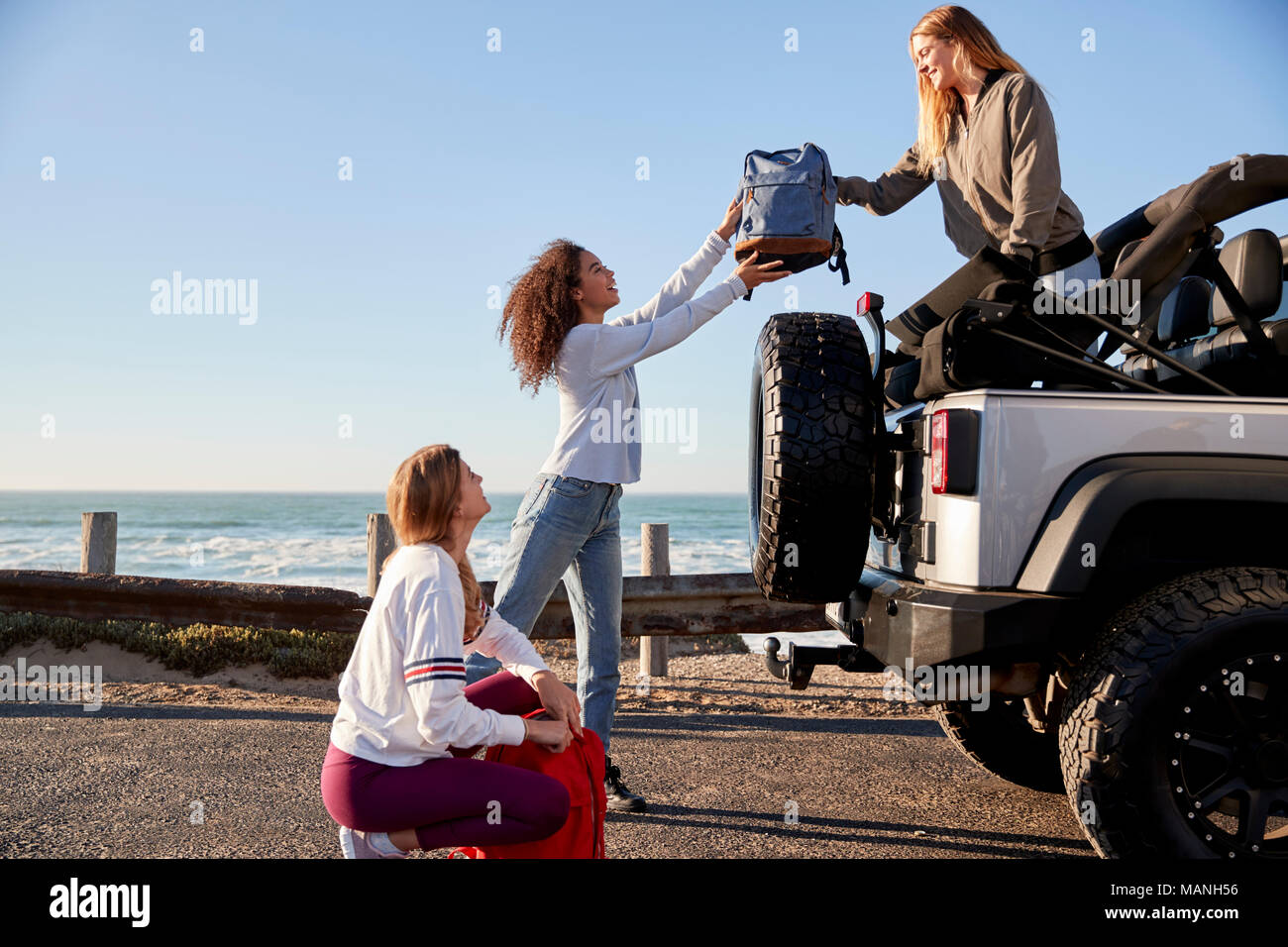 Drei junge Erwachsene Freundinnen Rucksäcke entladen aus ein Auto Stockfoto