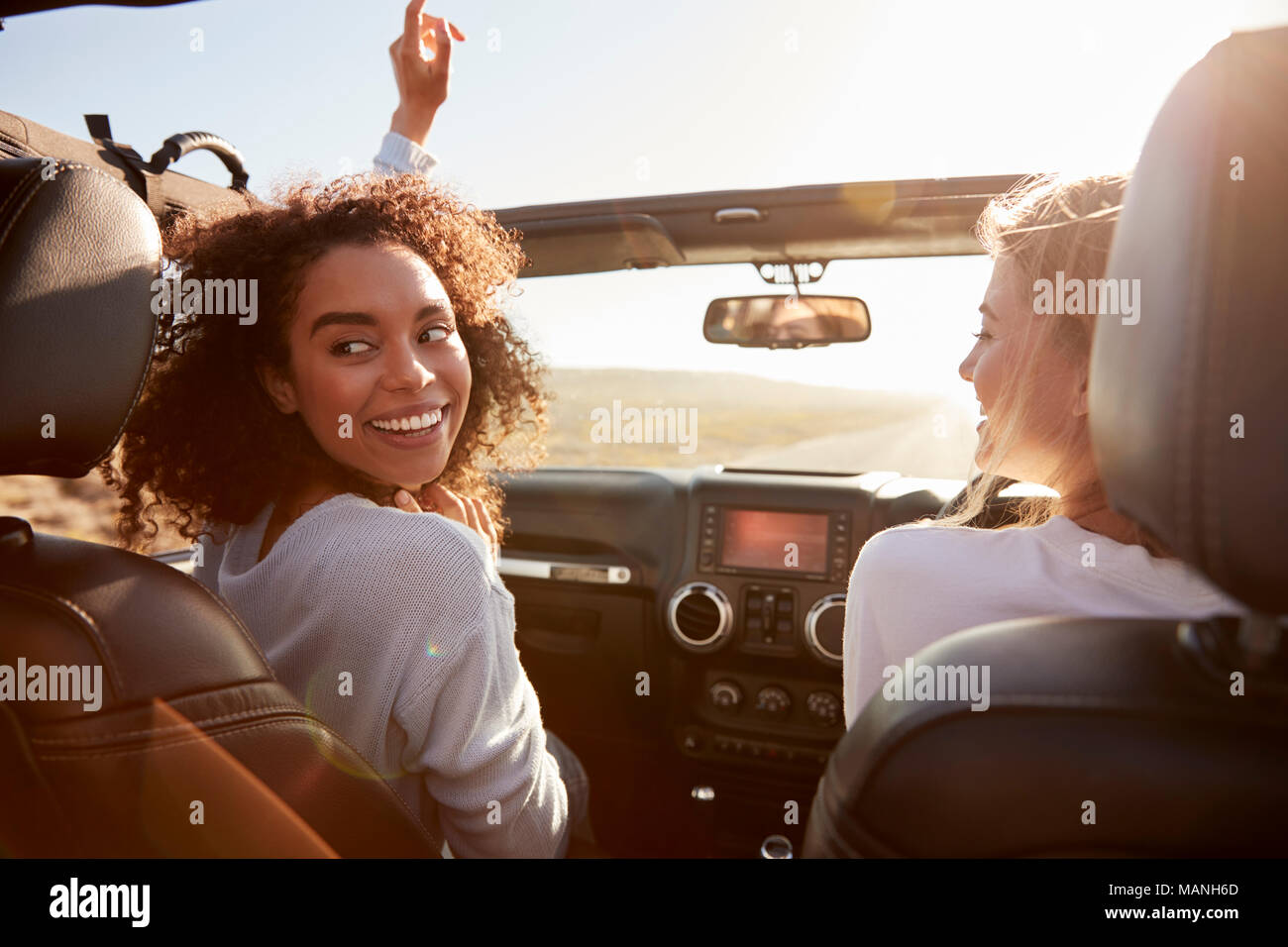 Zwei Freundinnen fahren mit Schiebedach geöffnet, eine Runde drehen Stockfoto