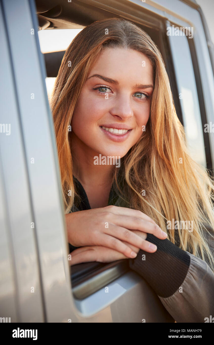 Junge weiße Frau zu Kamera schaut aus dem offenen Fenster des Autos Stockfoto