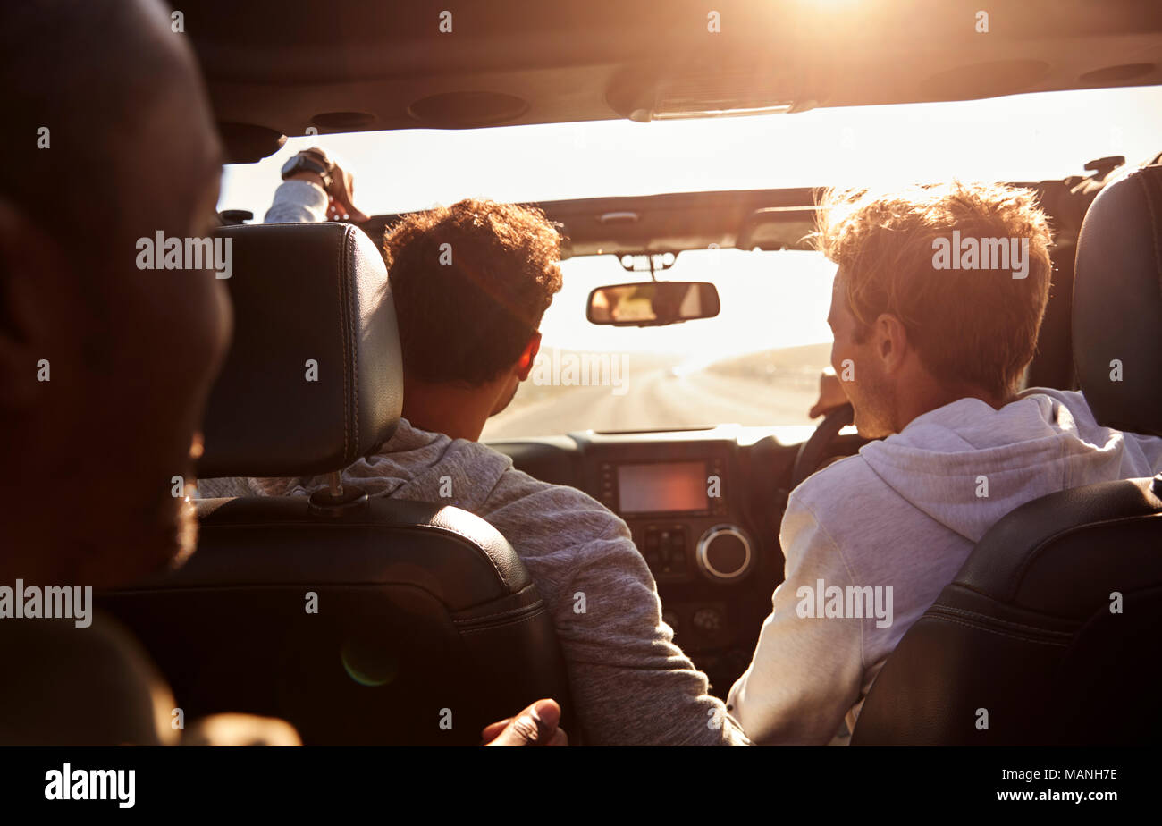 Drei junge erwachsene Männer fahren in einem Auto mit Schiebedach Stockfoto