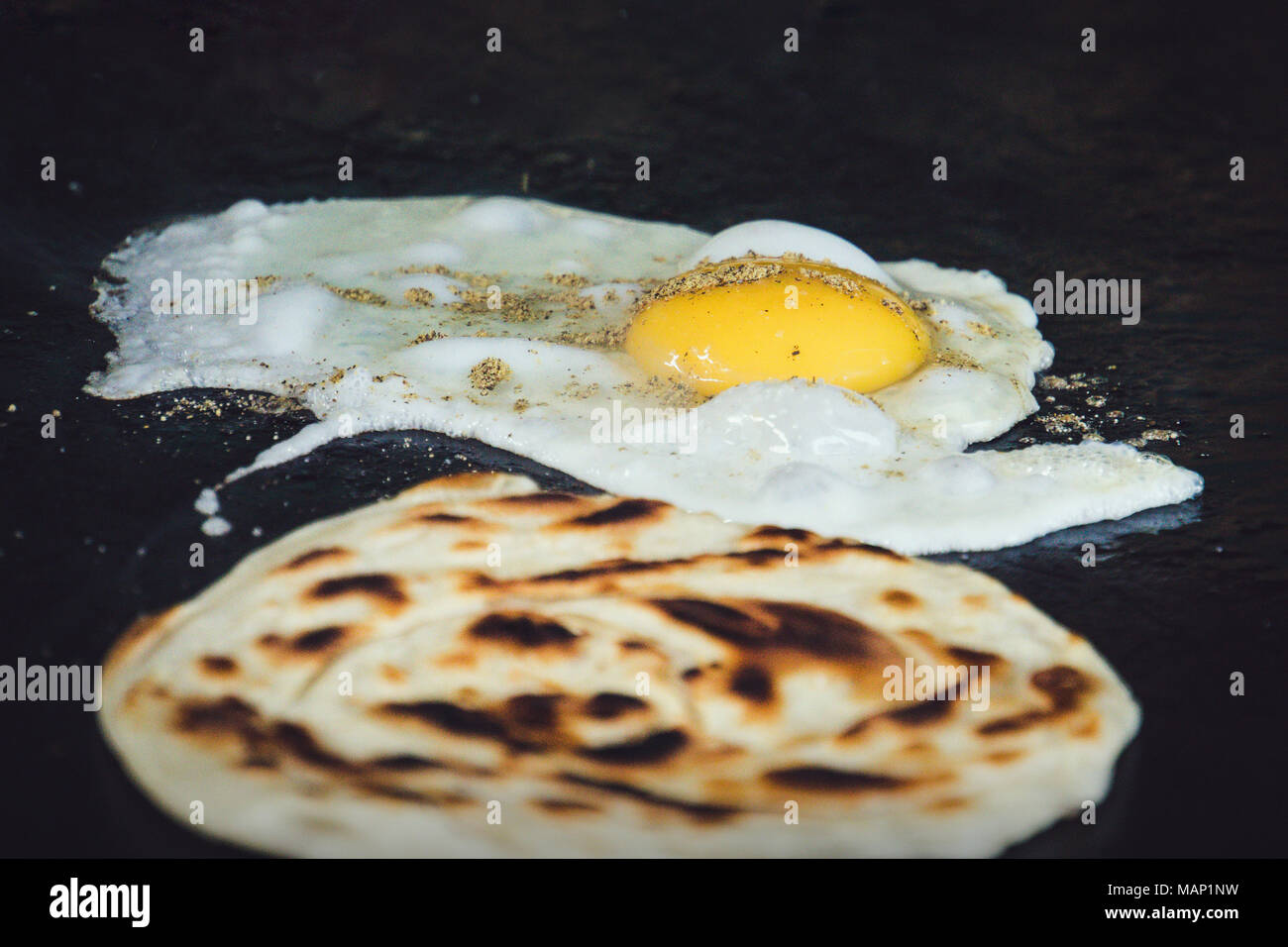 Pfanne den Teig. Traditionelles Indisches Fladenbrot ist mit Ei gebraten. Indisches Frühstück. Street Food in Indien. Omelette, Omelett, Rührei, Spiegelei Stockfoto