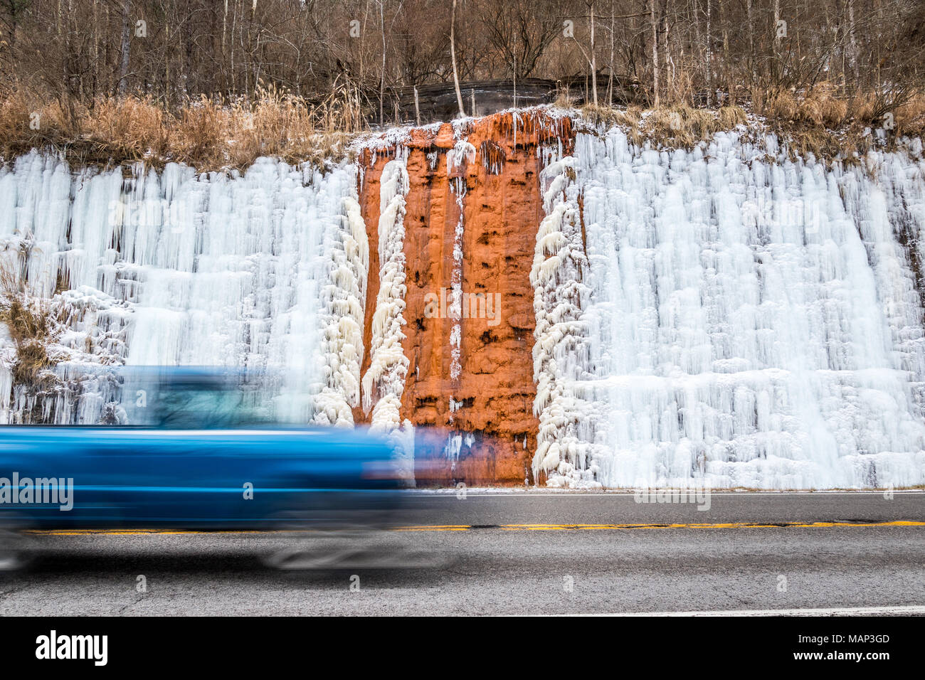 Ein blaues Fahrzeug fährt vorbei an einem Acid Mine Drainage Seite neben einer Autobahn. Stockfoto