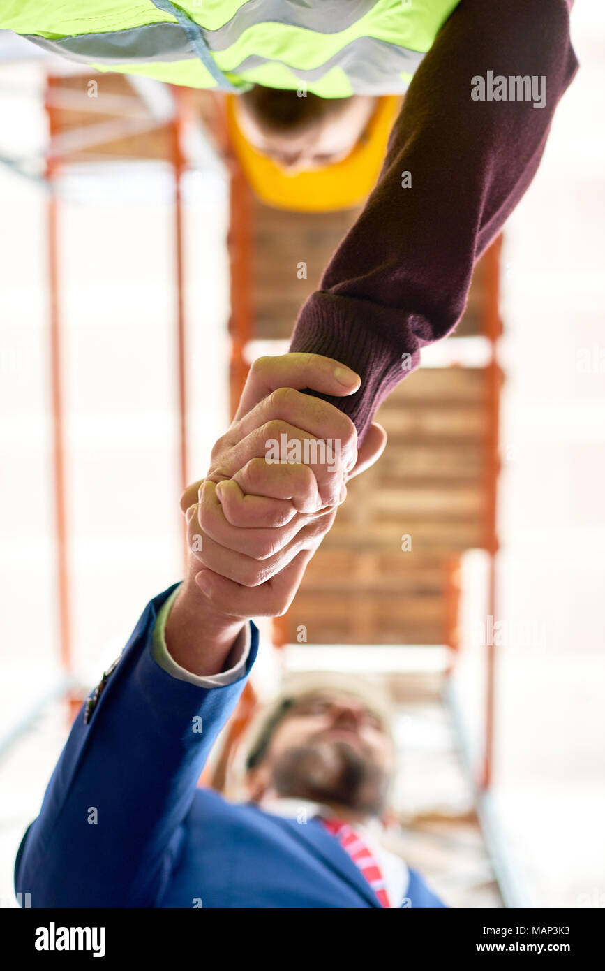 Geschäftsmann Händeschütteln mit Arbeiter Stockfoto