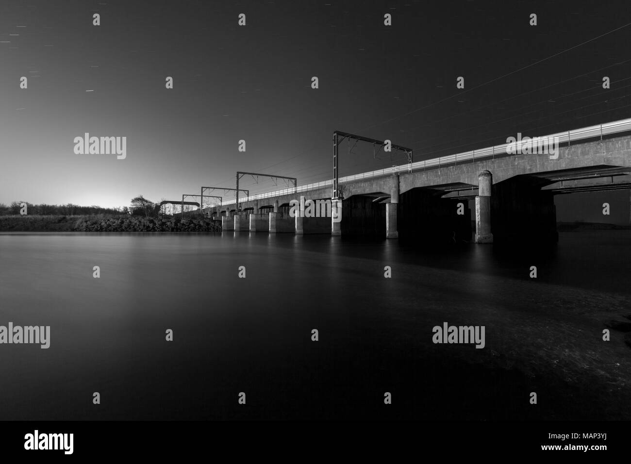 Der Eisenbahnviadukt über den Fluss Esk bei Mossband (nördlich von Carlisle) mit einem Bahnübergang bei Nacht Stockfoto