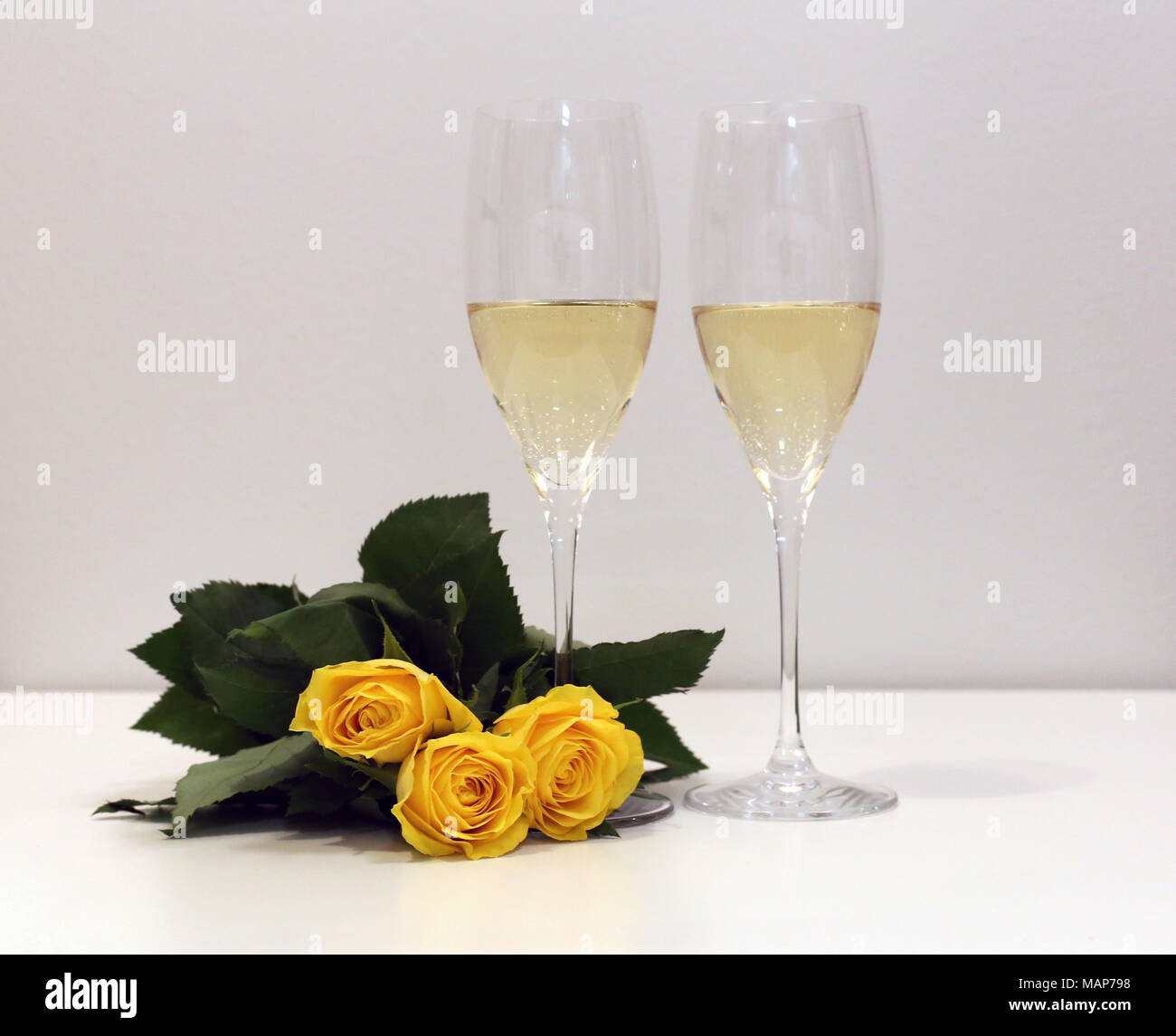 Zwei Gläser Champagner/Sekt mit drei gelbe Rosen. Perfekte still life Foto für Frühjahr, Sommer oder jede Art von Feier. Stockfoto