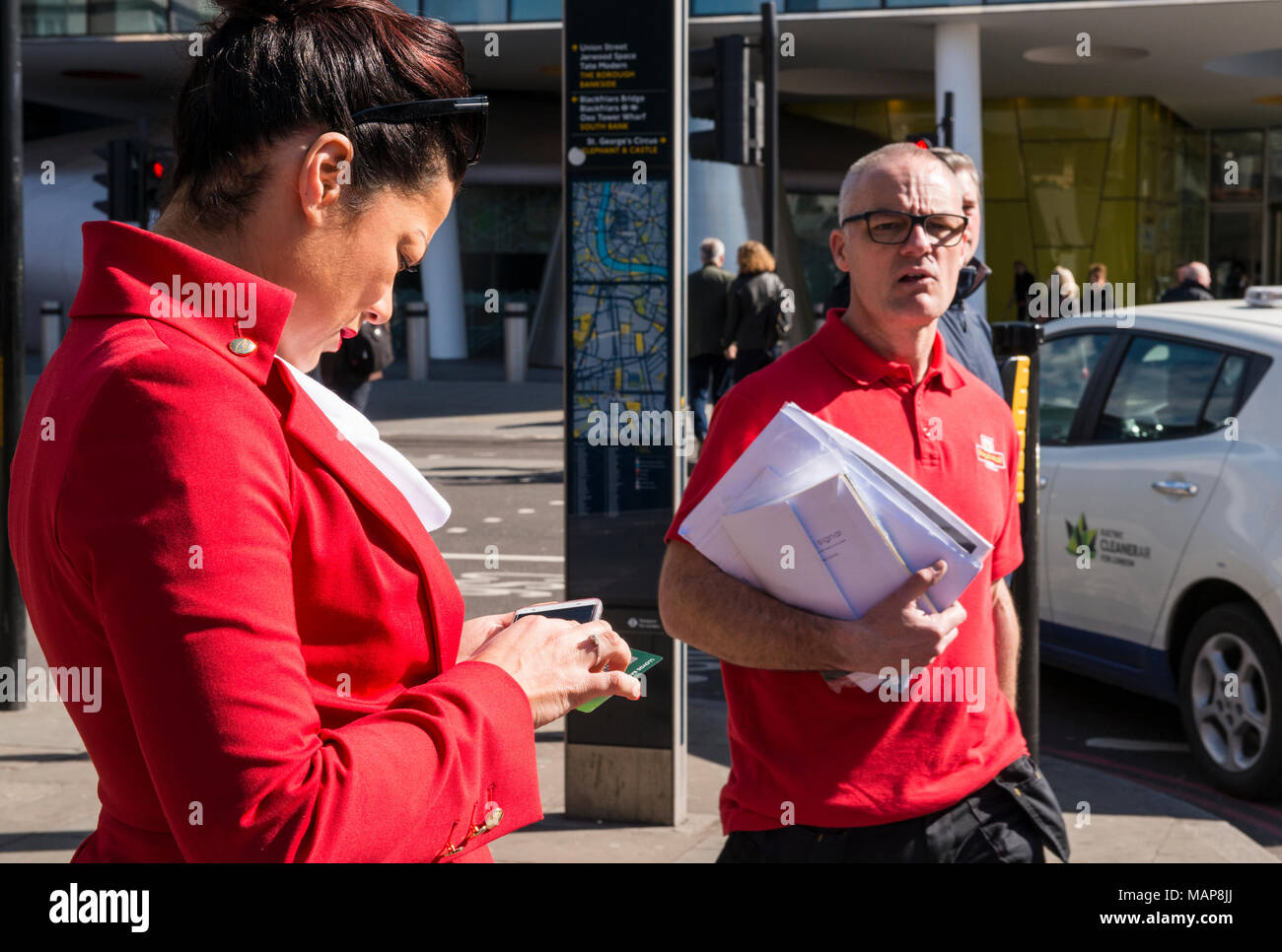 Mann und Frau sowohl in Rot als auf der Straße, London, England, Großbritannien Stockfoto