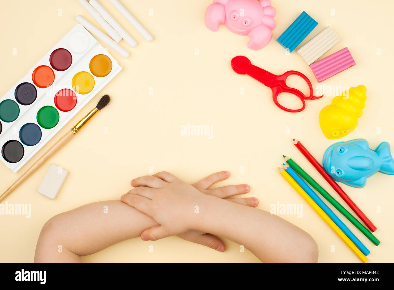 Das Kind sitzt am Tisch mit Objekten für Kreativität, Zeichnung und Hobbys, die Ansicht von oben Stockfoto
