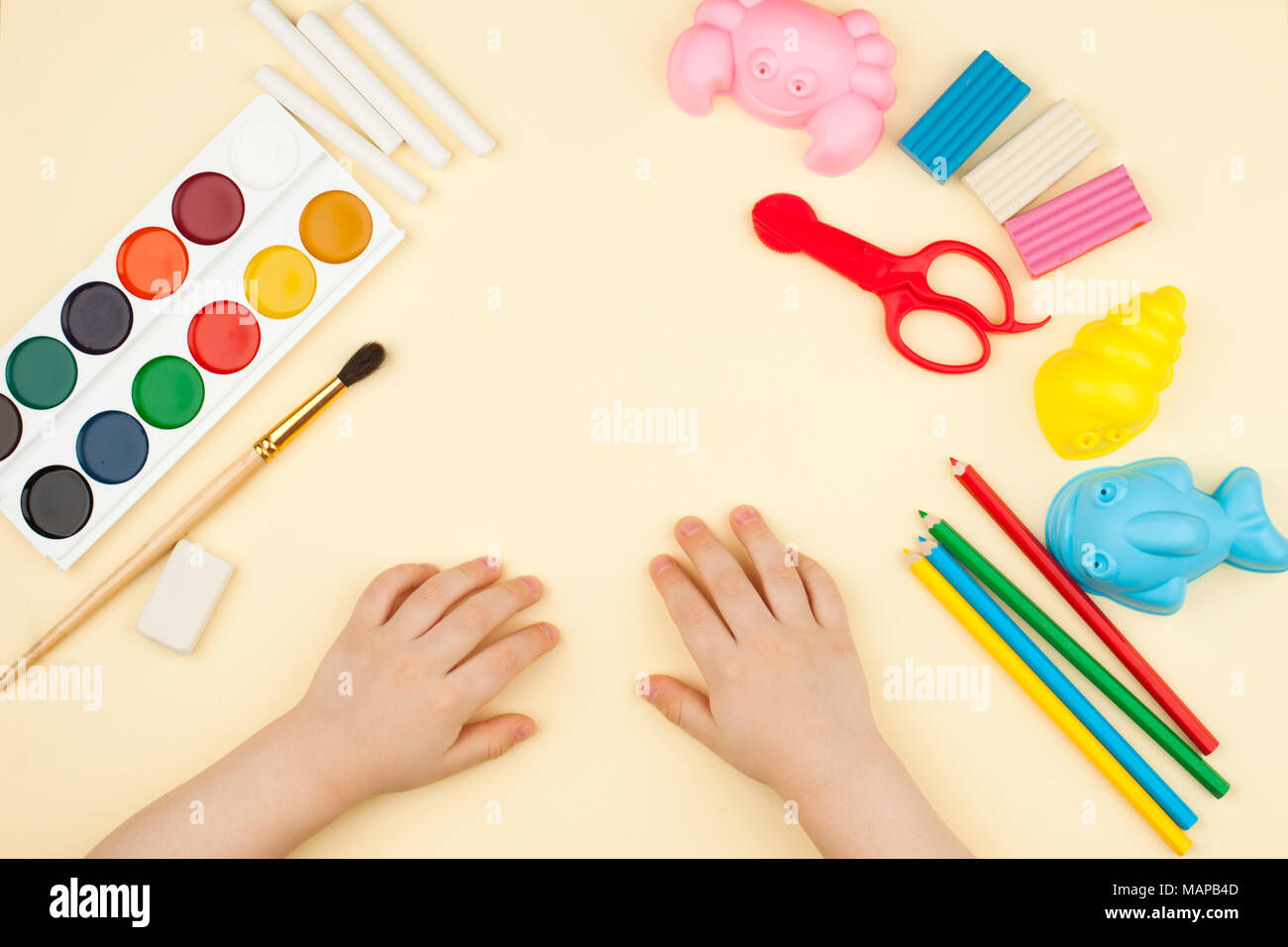Das Kind sitzt am Tisch mit Objekten für Kreativität, Zeichnung und Hobbys, die Ansicht von oben Stockfoto