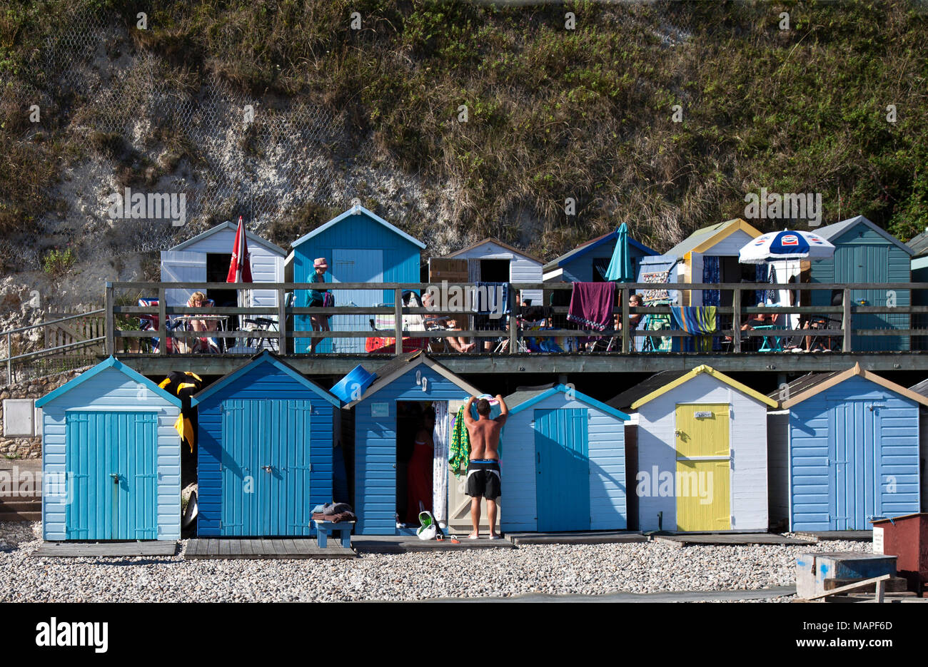 Ein Markenzeichen der Britischen Strände, bunte Badehäuschen können Eigentum sein, vermietet oder Vergangenheit, die durch die Familien. Diese Linie Den hinteren Teil des Bieres Strand. Stockfoto