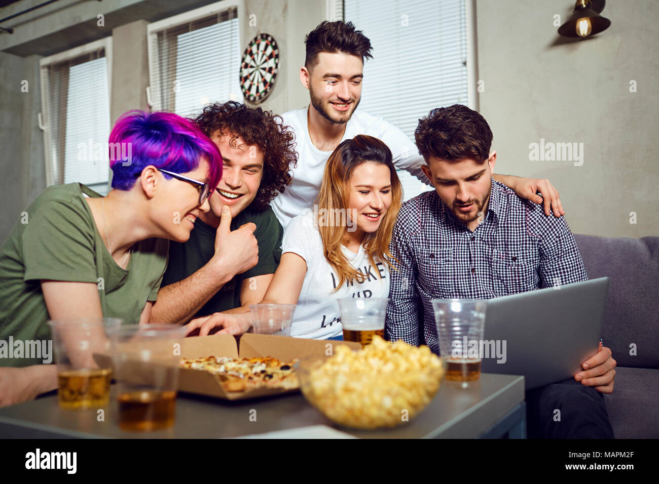 Eine Gruppe von Freunden der Schüler in Freizeitaktivitäten mit einem Laptop zusammen Stockfoto