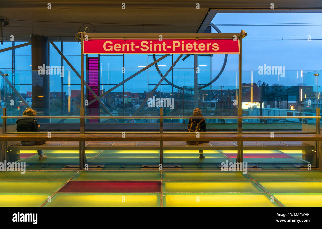 Zwei Personen auf einer Plattform der Gent Bahnhof mit beleuchtetem Fußboden und grelle Farben, Belgien wartet. Stockfoto