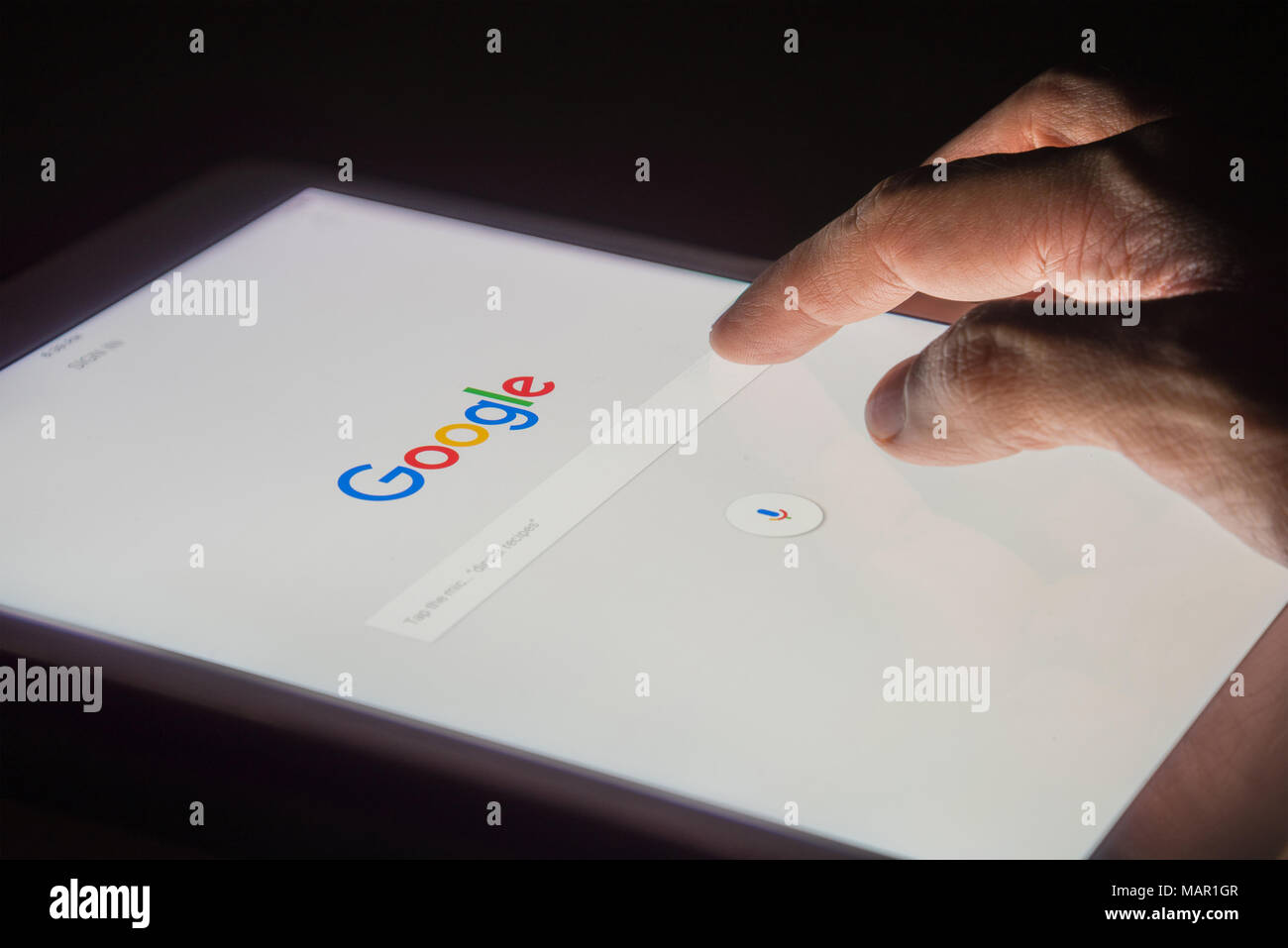 BANGKOK, THAILAND - 14. FEBRUAR 2017: die Hand eines Mannes berührt auf Tablet in der Nacht für die Suche bei Google Search Engine. Google ist die Po Stockfoto