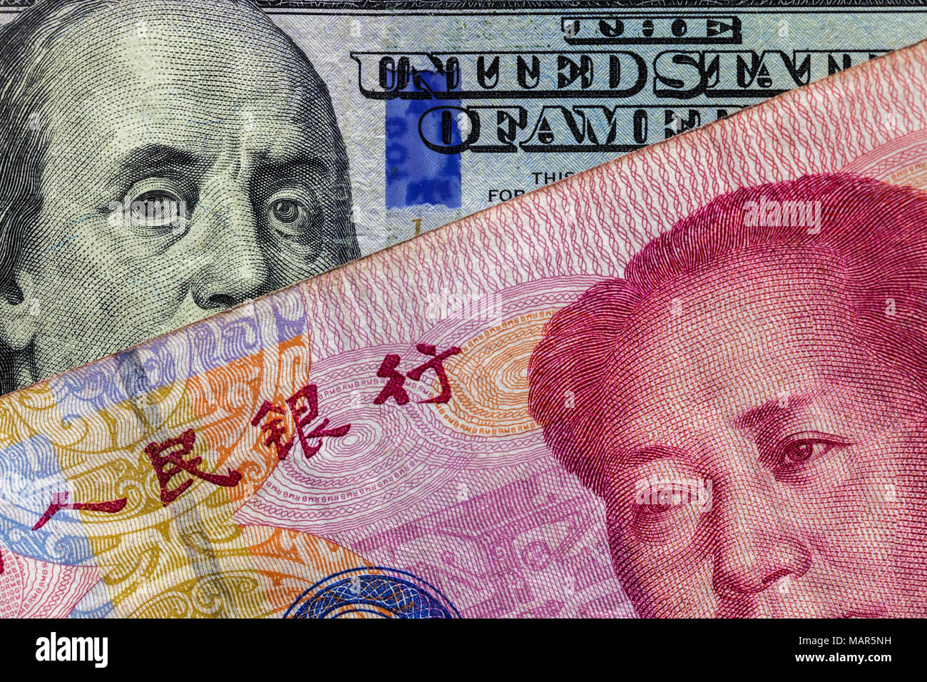 Nahaufnahme von 100 Yuan Banknote über Hundert Dollar Banknote mit Schwerpunkt auf Portraits von Benjamin Franklin und Mao Tse-tung/USA vs China trade Krieg Stockfoto