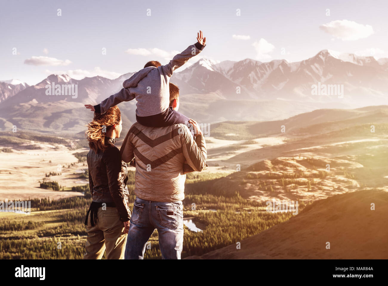 Glückliche Familie mit kleinen Sohn steht gegen Berge Sonnenuntergang. Reisen Tourismus Abenteuer Konzept Stockfoto