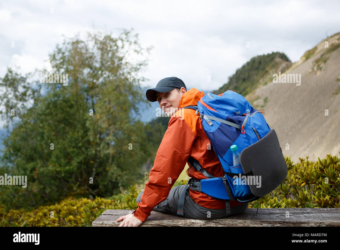 Foto von sportlichen lächelnden Mann mit Rucksack auf dem Hintergrund der Berg Stockfoto