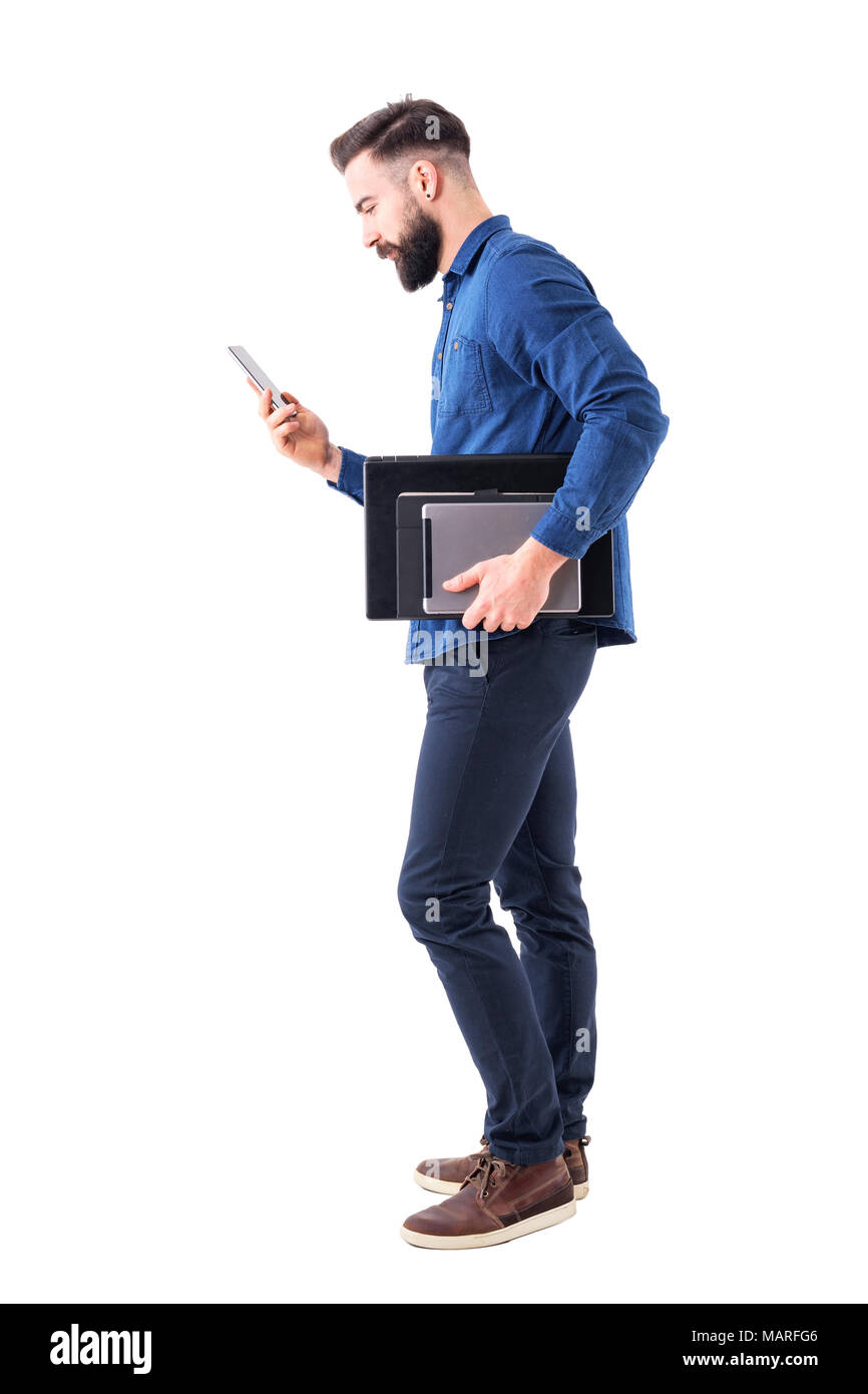 Professionelle männliche exekutive Kontrolle Telefon, Tablet-PC und Laptop unter dem Arm. Von der Seite. Voller Körper auf weißem Hintergrund. Stockfoto