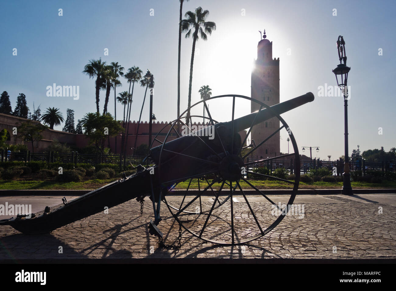 Vintage Cannon vor der Koutoubia Moschee und Palmen bei Sonnenuntergang, Marrakesch, Marokko Stockfoto
