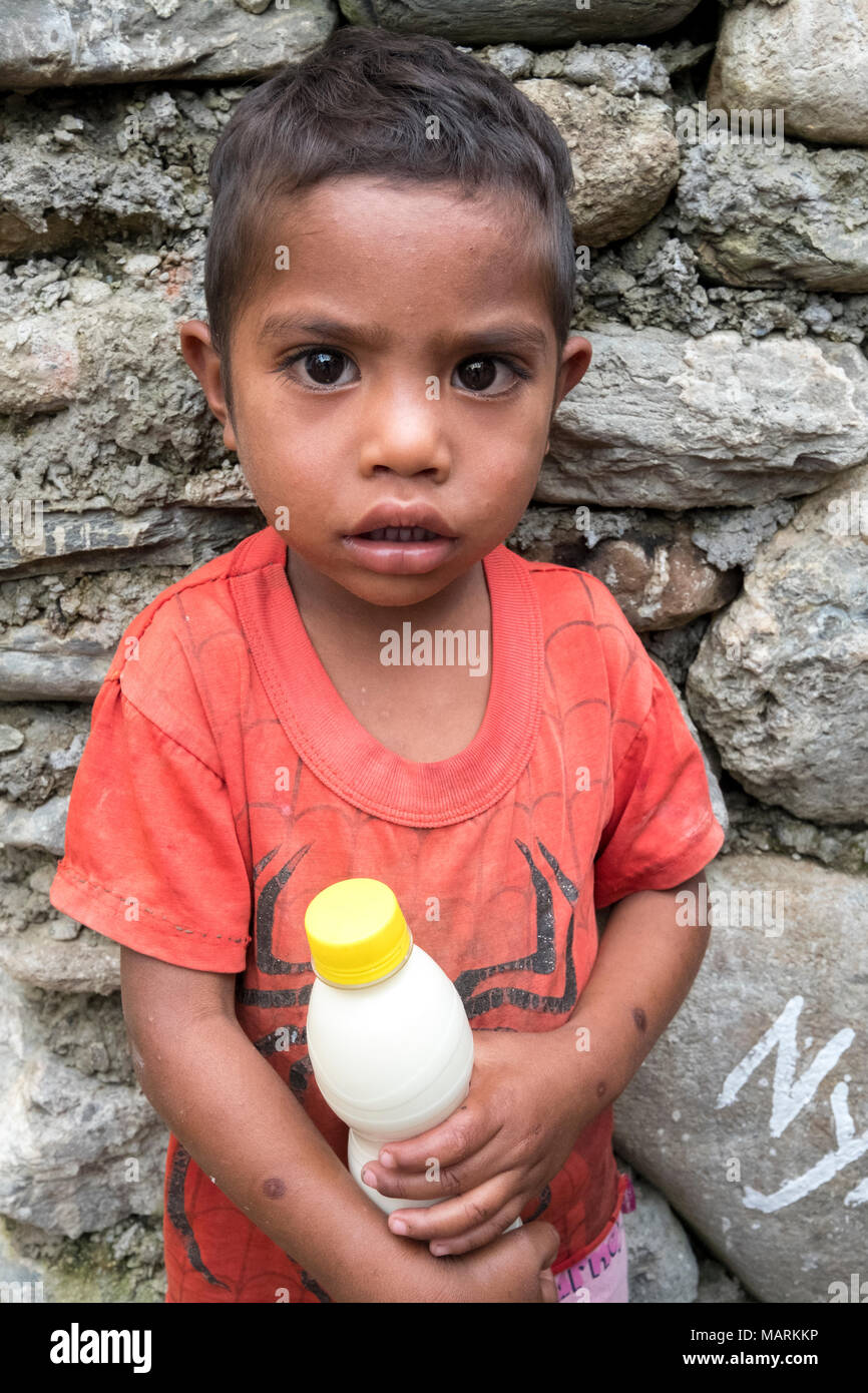 Ein kleiner Junge hält eine Flasche Milch in der Jesuit Ernährungsprogramm, welche Nahrungsmittel für unterernährte Kinder in Cocoa Village verteilt, Ermera, Timor-Leste. Viele Dorfbewohner in den ländlichen Gebieten haben große Familien, die sie nicht unterstützt, so dass eine grosse Zahl der Kinder an Unterernährung leiden. Dieses Ernährungsprogramm ist fast täglich auf drei Dörfer im Distrikt Ermera durchgeführt. Stockfoto
